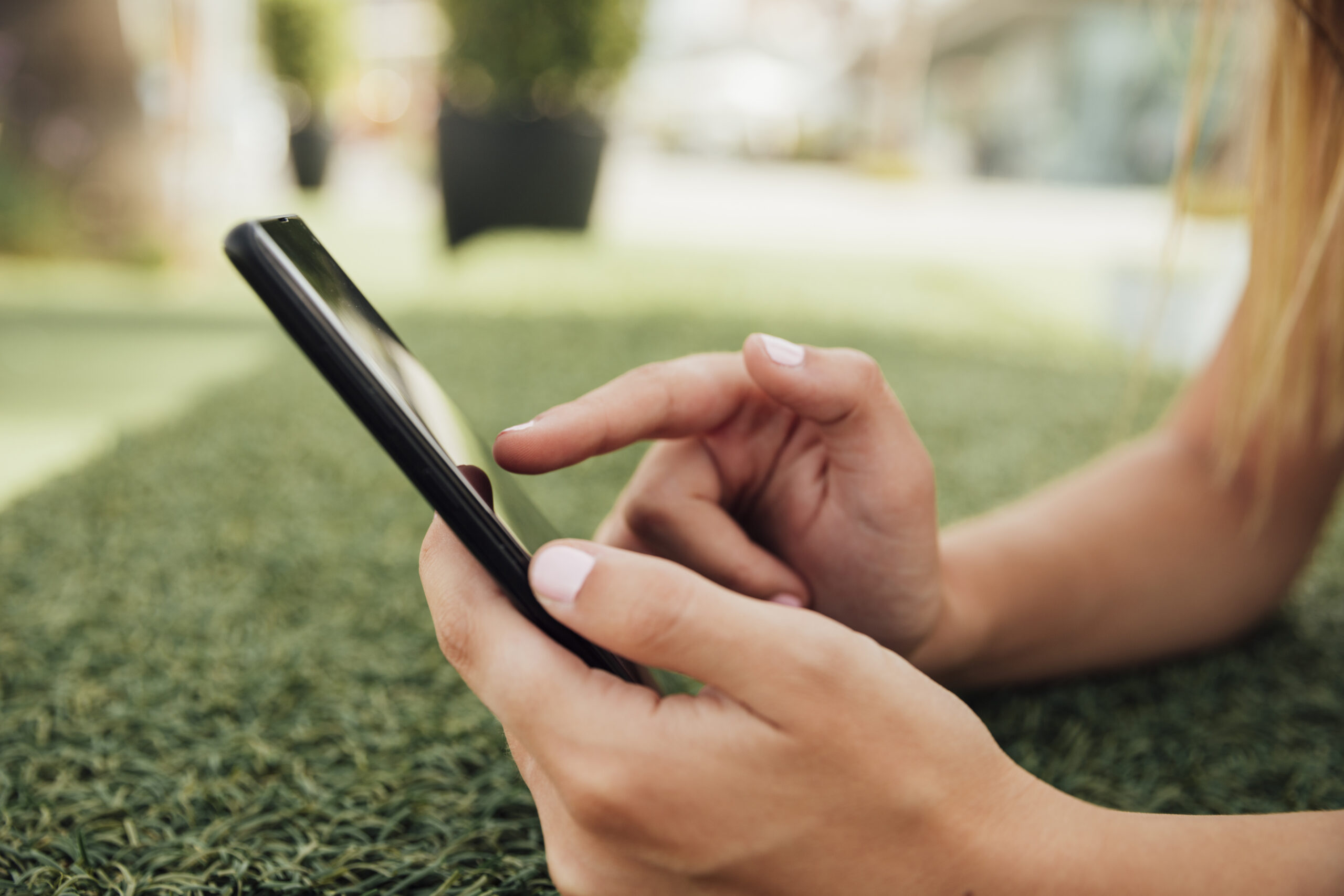mains-de-femme-avec-téléphone-portable-sur-herbe